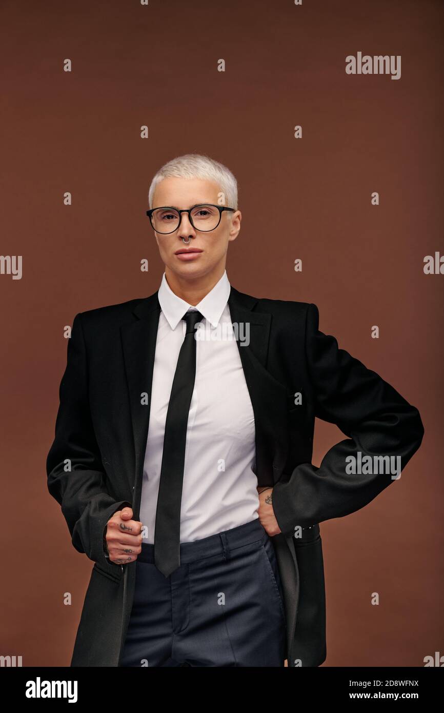Joven mujer con estilo en traje negro elegante y gafas en aislamiento  Fotografía de stock - Alamy
