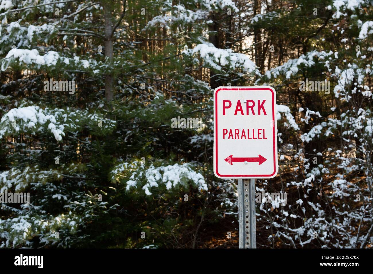 Letrero de estacionamiento paralelo rojo y blanco en un estacionamiento en el desierto en las Montañas Adirondack, NY EE.UU. En invierno Foto de stock