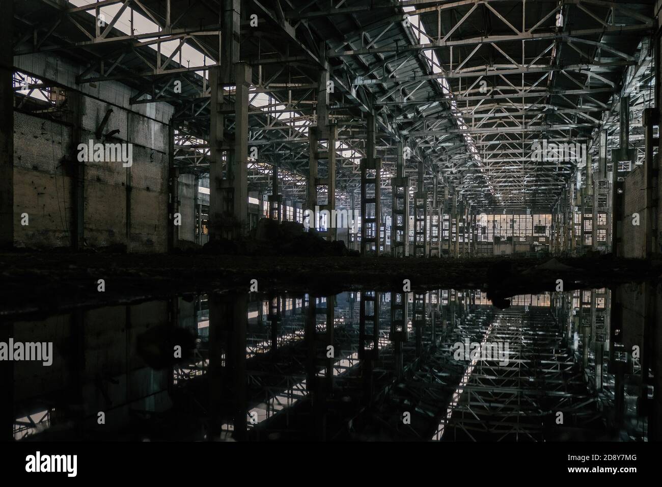 Dentro de un sucio inundado abandonado edificio industrial arruinado con reflexión de agua Foto de stock