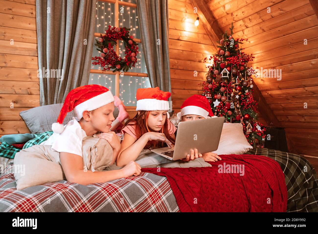 tres niños en pijamas en la cama con video chat Con la familia en la mañana  de Navidad Fotografía de stock - Alamy
