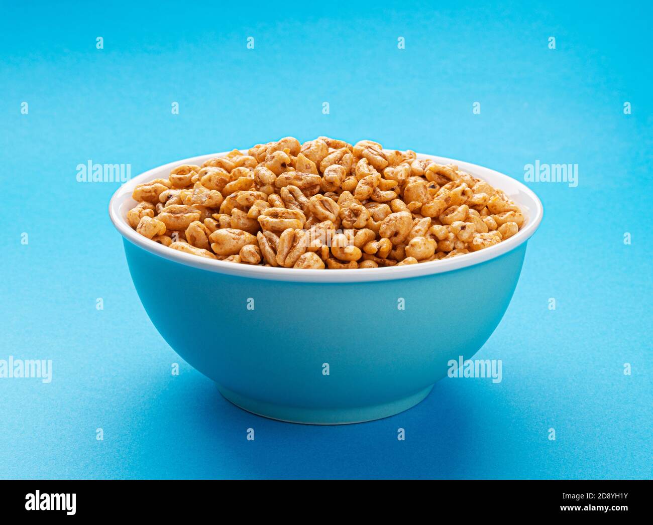 Cereal de trigo hinchado aislado sobre fondo azul Foto de stock