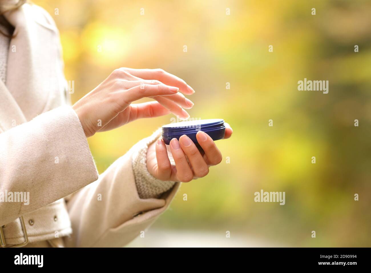 Primer plano de la mujer se secan las manos en otoño sosteniendo un botella hidratante lista para aplicar crema Foto de stock