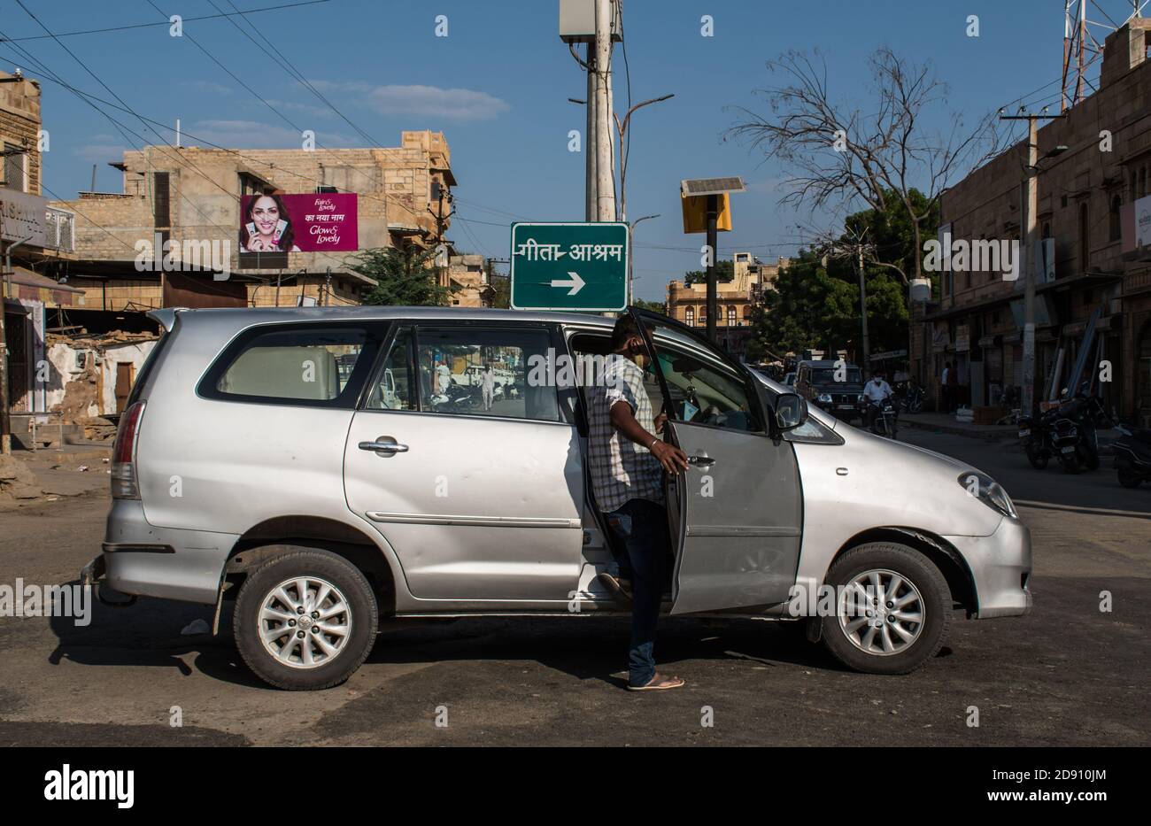 Jaisalmer, Rajasthan / India - Septiembre 28 2020 : el hombre se está adentrando en un coche estacionado en medio de la carretera Foto de stock