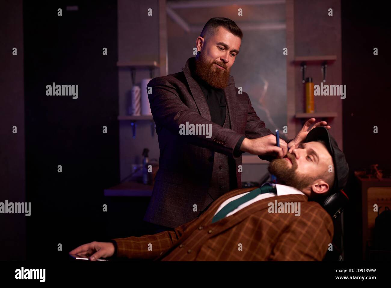 concepto de tienda de belleza para hombres. peluquería profesional afeitando la barba a los clientes ricos en una peluquería, cortes de pelo brutales Foto de stock