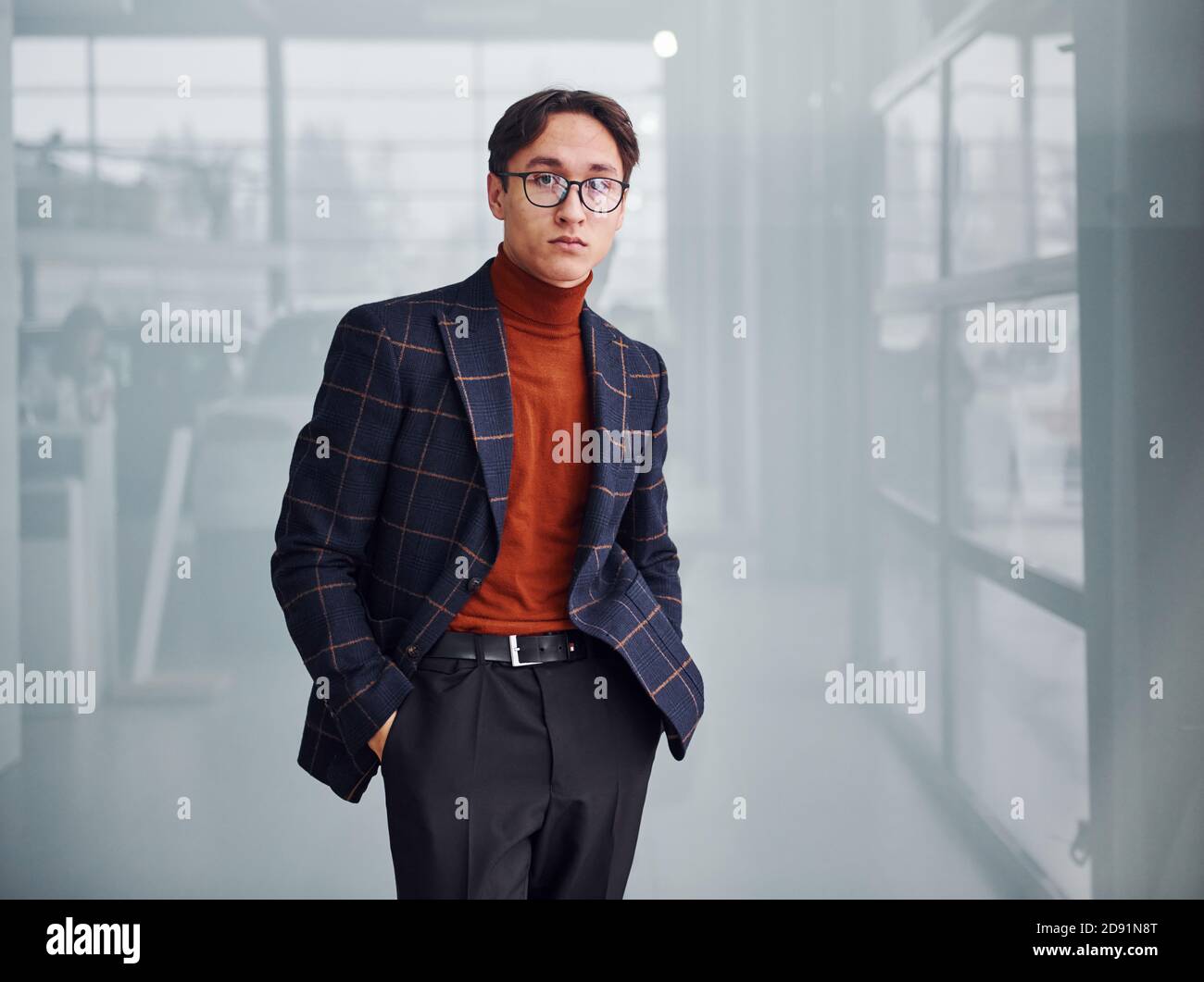 Joven hombre de negocios en traje de lujo y ropa formal posando para la  cámara en interiores Fotografía de stock - Alamy