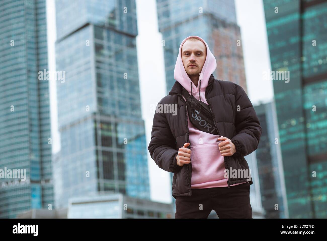 Hombre guapo informal con chaqueta negra y sudadera con capucha rosa de pie  en una vista de rascacielos Fotografía de stock - Alamy
