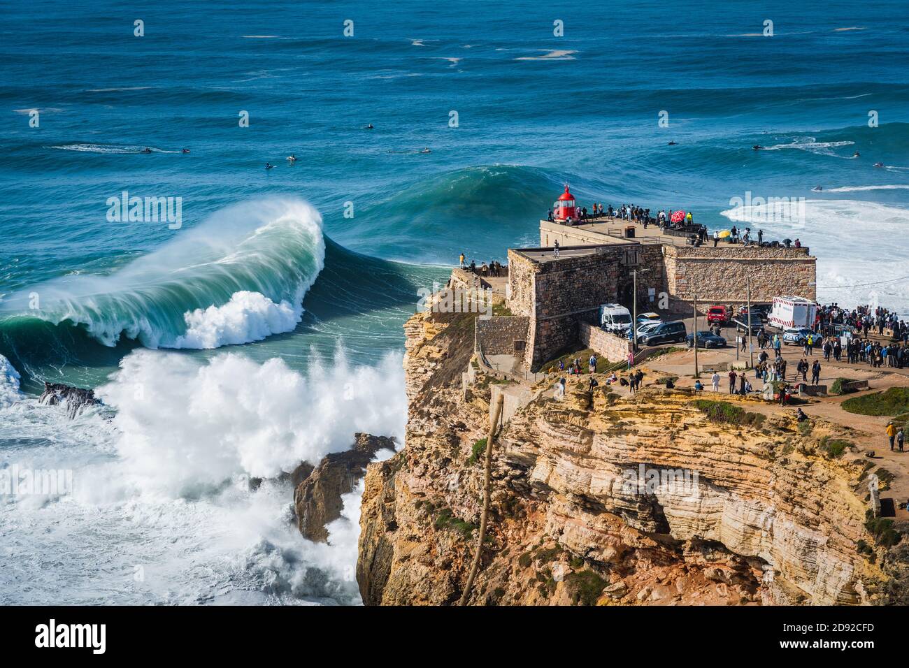 Grandes olas rompiendo cerca del fuerte faro de Nazare en Nazare, Portugal. Nazare es famoso por tener las olas más grandes del mundo. Foto de stock