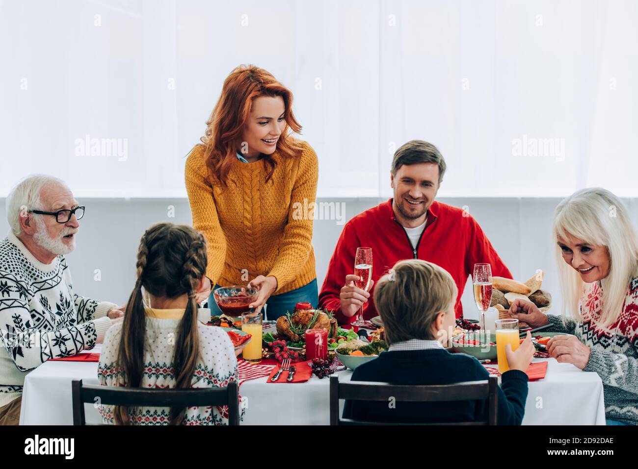 Familia hablando y sentado en mesa festiva con cena de acción de gracias en casa Foto de stock
