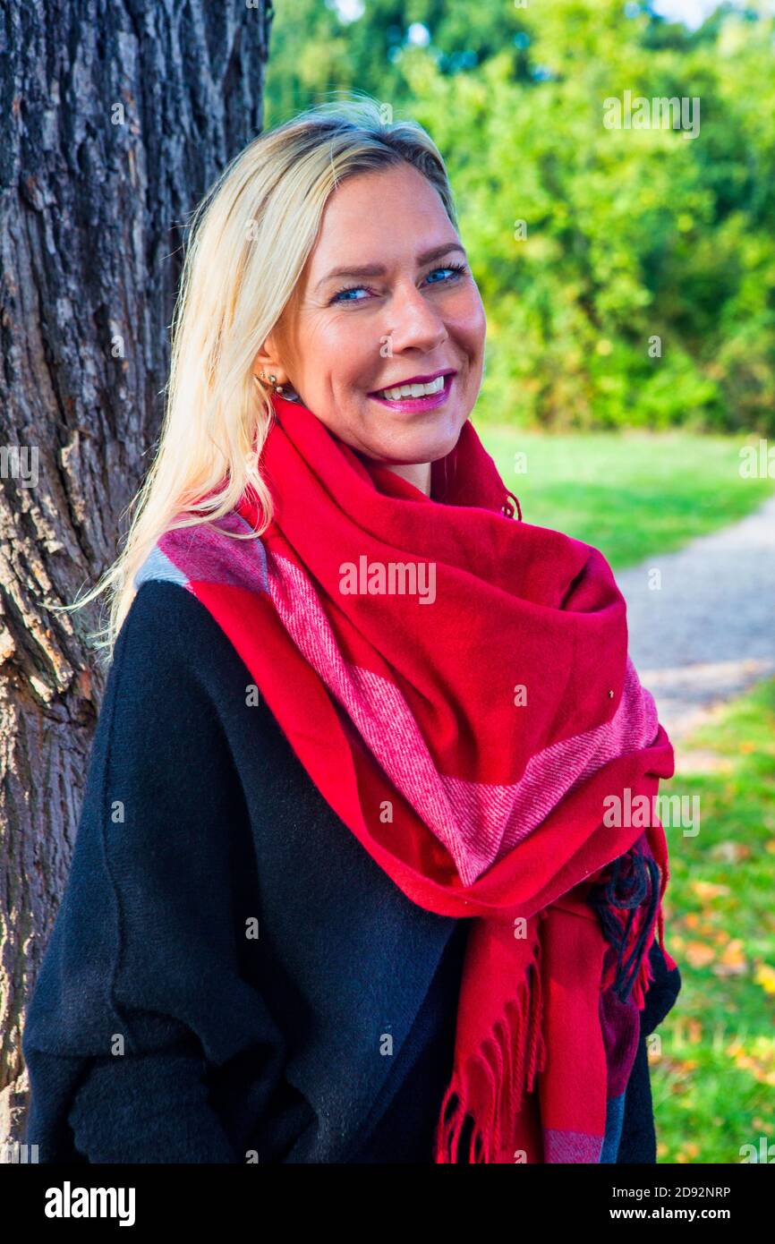 retrato de mujer sonriente en bufanda al lado un árbol Fotografía de stock - Alamy