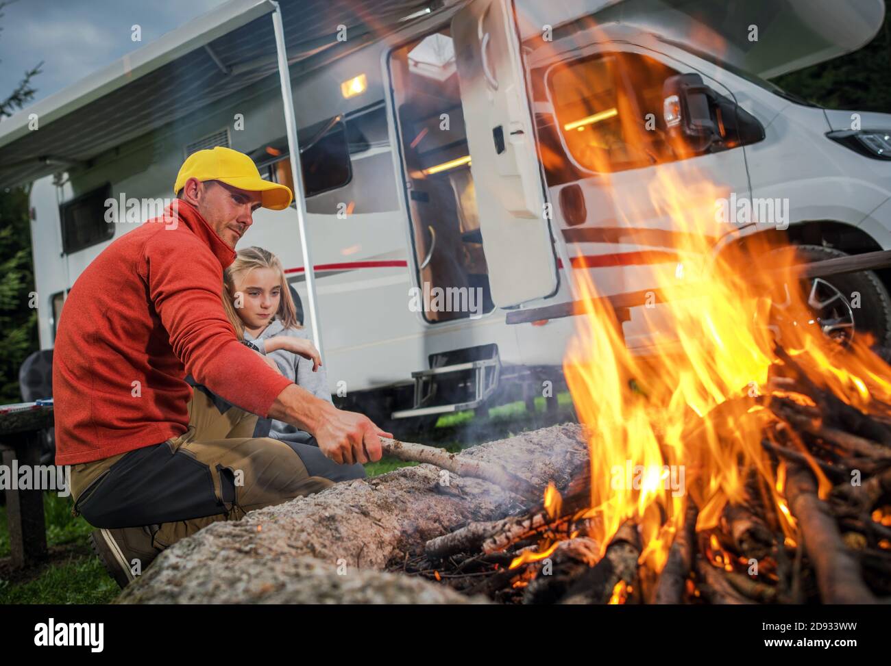Vehículo Recreativo RV Camper Camping y tiempo Familiar. Padre caucásico y su hija Colgante junto a Campfire en su campo de estacionamiento RV. Clase C Mot Foto de stock