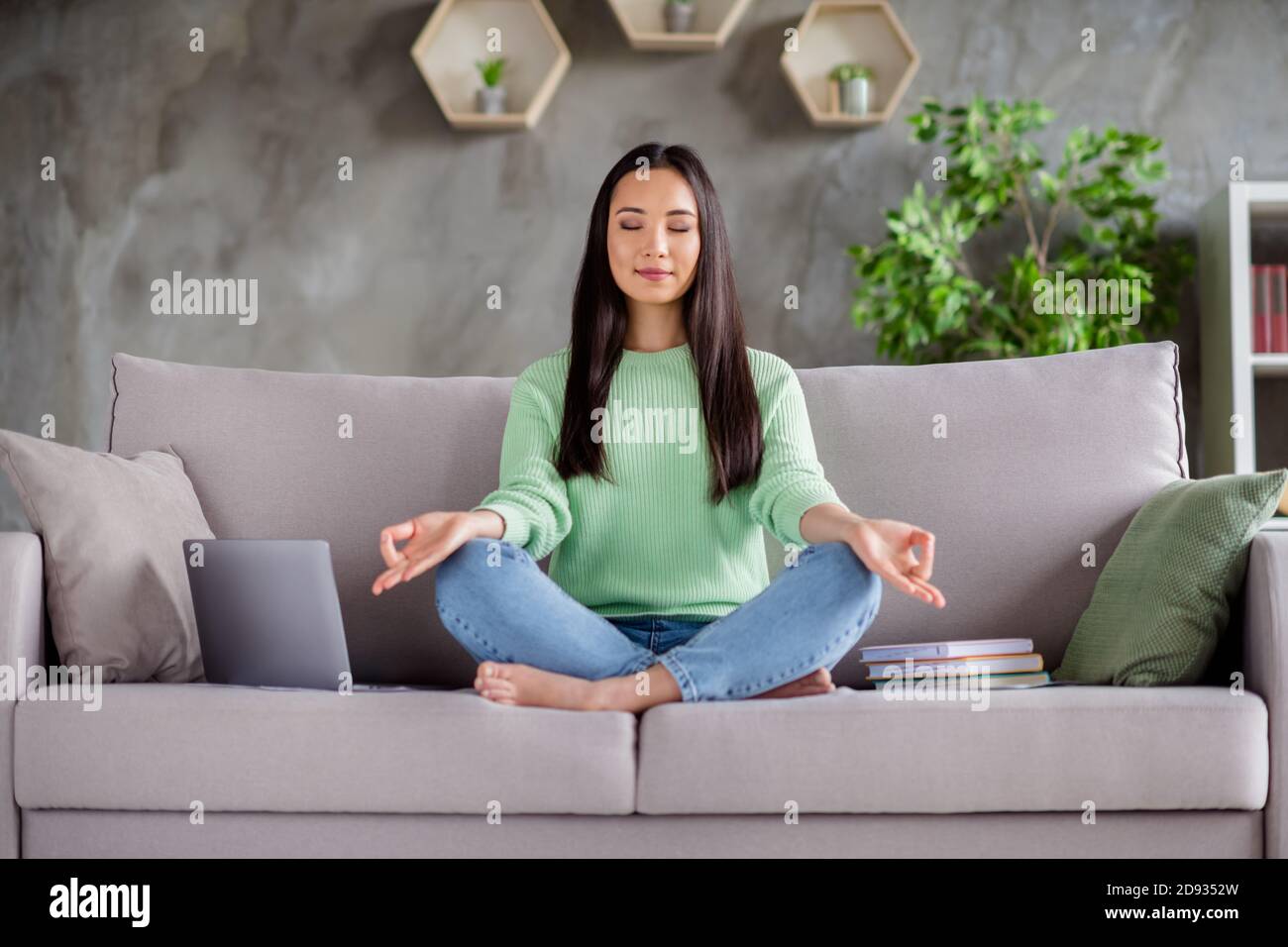 Foto de tamaño completo de la tranquila y enfocada niña coreana sentarse  sofá piernas cruzadas plegadas descalzo meditar trabajo romper pausa en  casa interior Fotografía de stock - Alamy