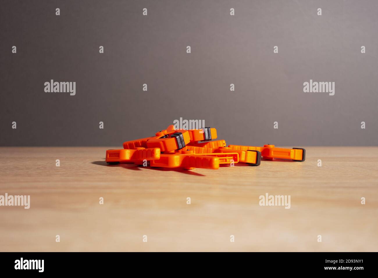 Tendedero, pinzas de carpintería de color naranja yacen sobre una mesa de madera. Foto de stock