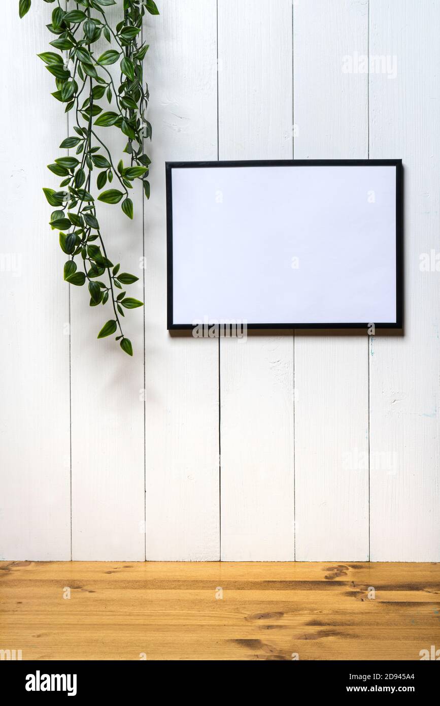 un marco negro en blanco y una hiedra en un blanco fondo de madera Foto de stock