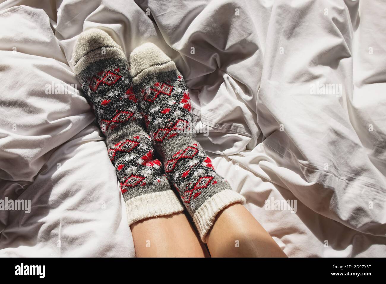 Mujer pies en calcetines de lana en la cama blanca Foto de stock