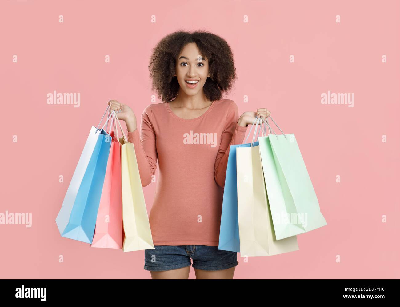 Feliz joven afroamericana en ropa casual mostrando un un montón de bolsas de compras multicolores Foto de stock