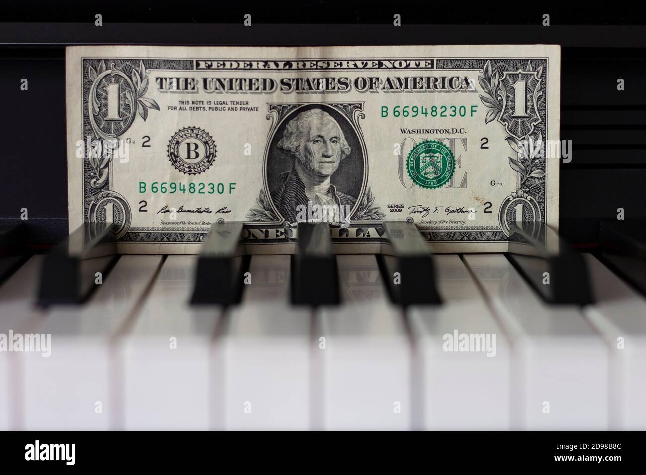 Billete de un dólar sobre las teclas del piano. El dólar como símbolo de la gestión económica mundial. Foto de stock