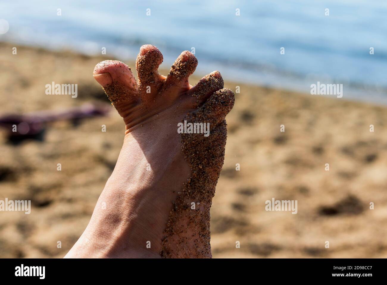 Parte del pie de la mujer en la arena, de cerca. Foto de stock