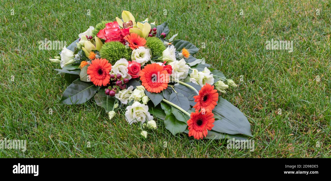 Arreglo de flores alargadas para el día de todos los Santos. Pedazo de la tumba en la hierba. Foto de stock