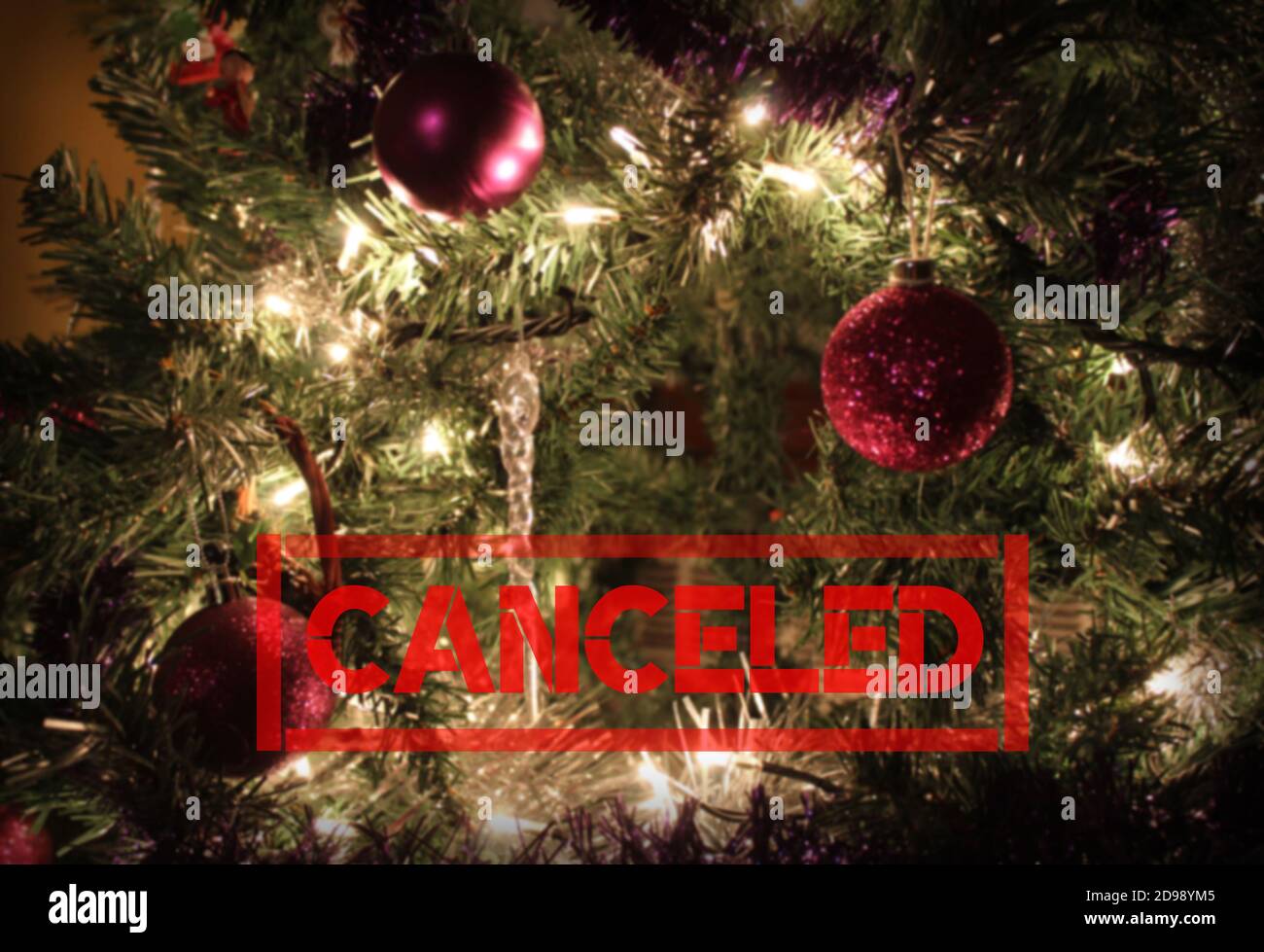 Texto 'cancelado' rojo sobre un fondo de árbol de Navidad decorado con desdibujado y copyspace. Temporada de vacaciones cancelada concepto debido al virus Corona Foto de stock