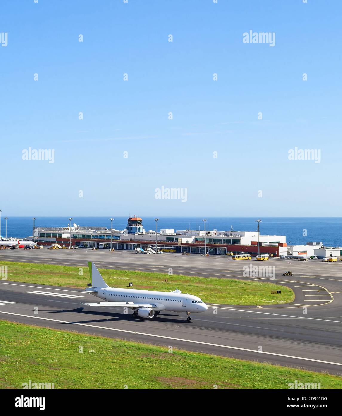 Avión en pista, terminal del aeropuerto en el fondo, paisaje marino, Madeira, Portugal Foto de stock