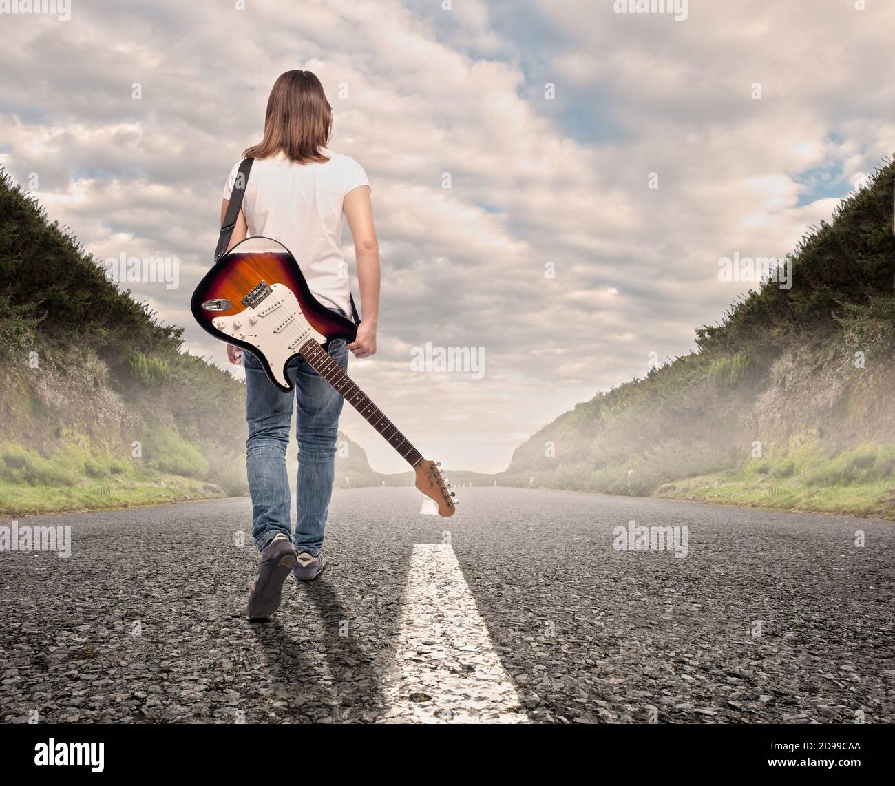 joven músico mujer con una guitarra eléctrica caminando en un carretera  Fotografía de stock - Alamy