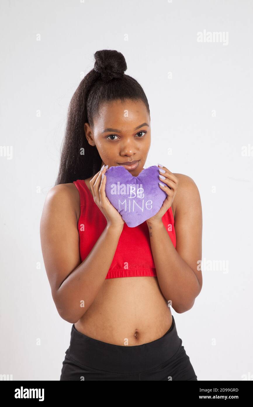 Mujer negra encantadora sosteniendo un corazón púrpura Foto de stock