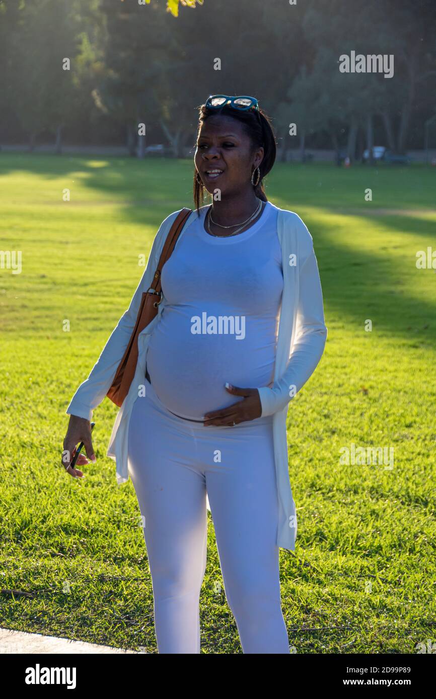 Una mujer embarazada de pie en un parque. Foto de stock
