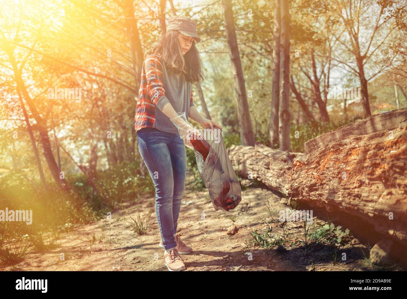 Mujer voluntaria ayuda a limpiar el bosque de basura plástica. El día