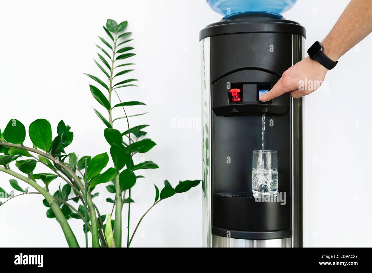 Dispensador de agua en la oficina, con la mano llenando un vaso de agua  Fotografía de stock - Alamy