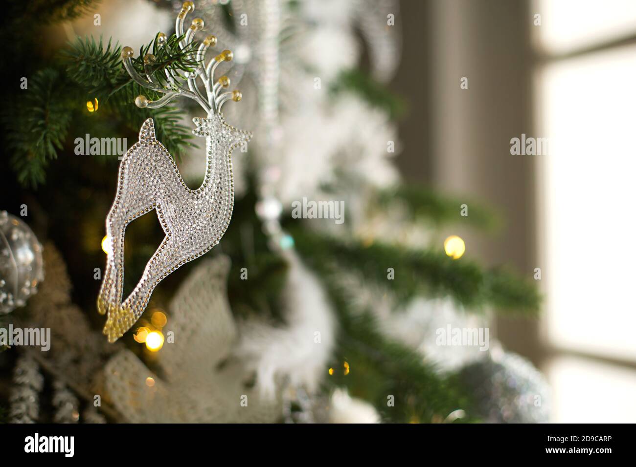 Colgante de ciervo de cristal transparente en árbol de Navidad con  guirnaldas de luces. Decoración de Navidad blanca, plumas, globos, flores,  cintas. Año nuevo, el atmo Fotografía de stock - Alamy