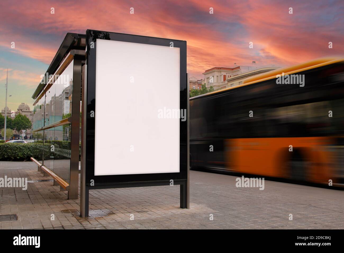 Parada de autobús con cartelera en blanco, con autobús de movimiento borroso al atardecer Foto de stock
