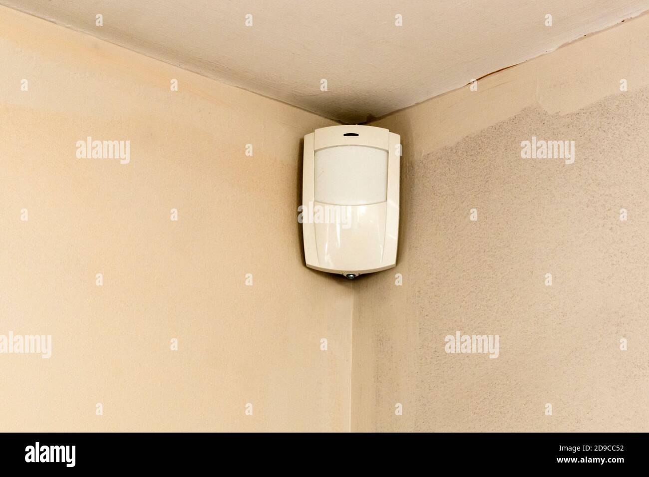 Detector de movimiento en la esquina de la habitación - parte de un sistema de seguridad para el hogar. Foto de stock