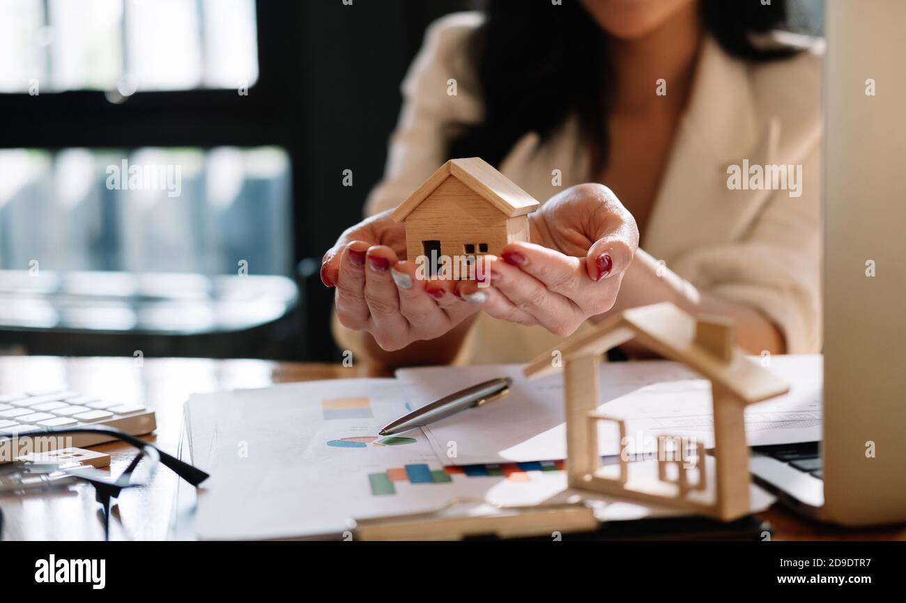 Agente inmobiliario con modelo de casa en casa de la oferta de hans. Seguro de propiedad y concepto de seguridad Foto de stock