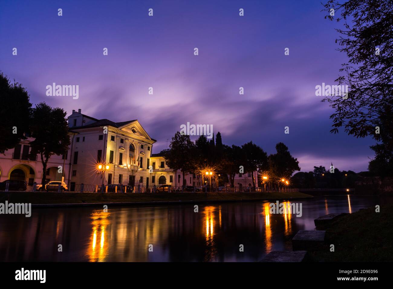 Vista pintoresca sobre el río Sile en el centro de la ciudad con un impresionante cielo púrpura y luces reflexiones en el Agua por la noche Treviso Italia Foto de stock