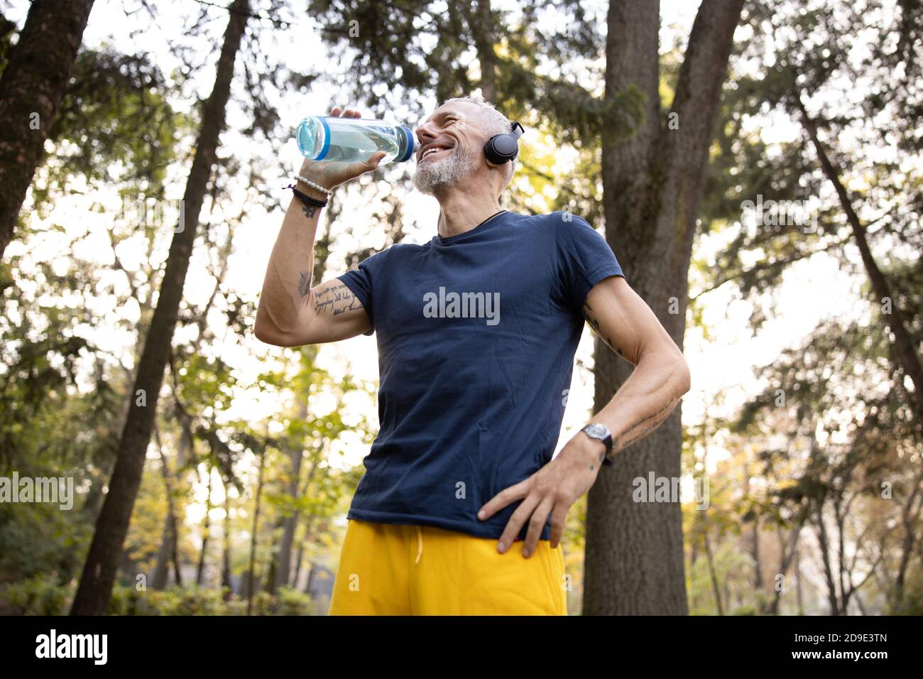 Hombre alegre saciando la sed después de entrenar al aire libre Foto de stock