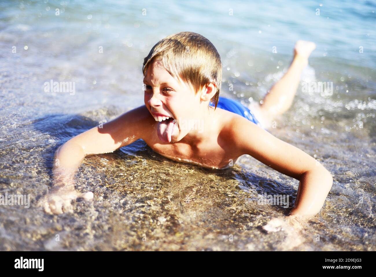 Emociones el niño se encuentra en aguas poco profundas en el mar alegre contento. Risas. El niño está de buen humor. Vacaciones. Espacio de copia. Foto de stock