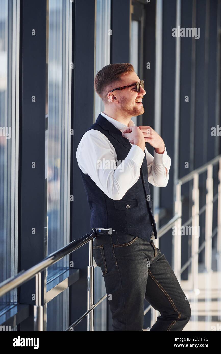 El hombre con ropa elegante y gafas de sol está de pie en el interior y  posando para la cámara Fotografía de stock - Alamy