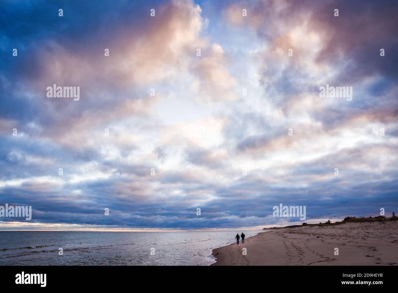 Un gran cielo se asoma sobre los caminantes de la playa en la costa norte de la Isla del Príncipe Eduardo, Canadá. Foto de stock