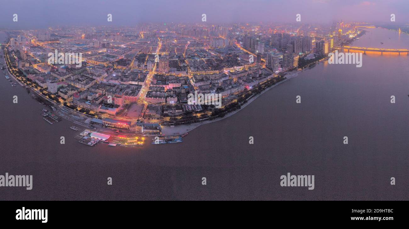 Una vista aérea de toda la zona urbana que se enciende a medida que llega la noche y las lámparas dentro de las casas, las luces de los automóviles y las farolas se encienden, Harbin c Foto de stock