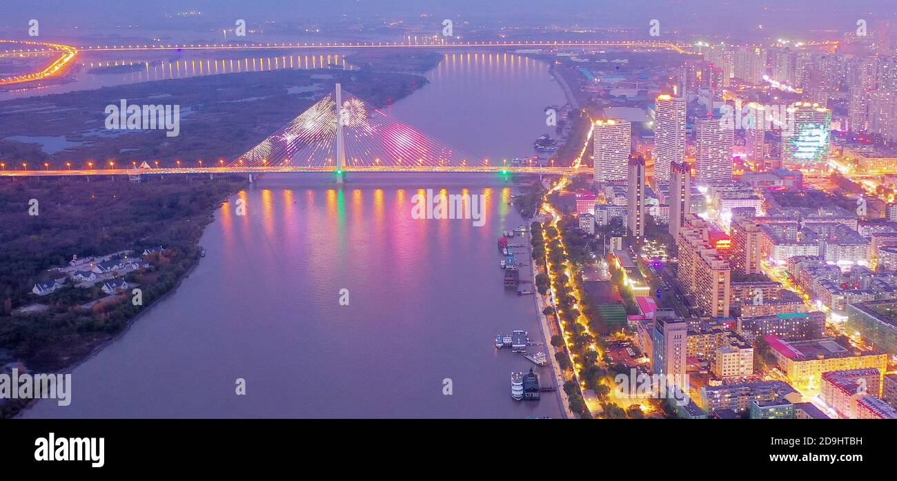 Una vista aérea de toda la zona urbana que se enciende a medida que llega la noche y las lámparas dentro de las casas, las luces de los automóviles y las farolas se encienden, Harbin c Foto de stock