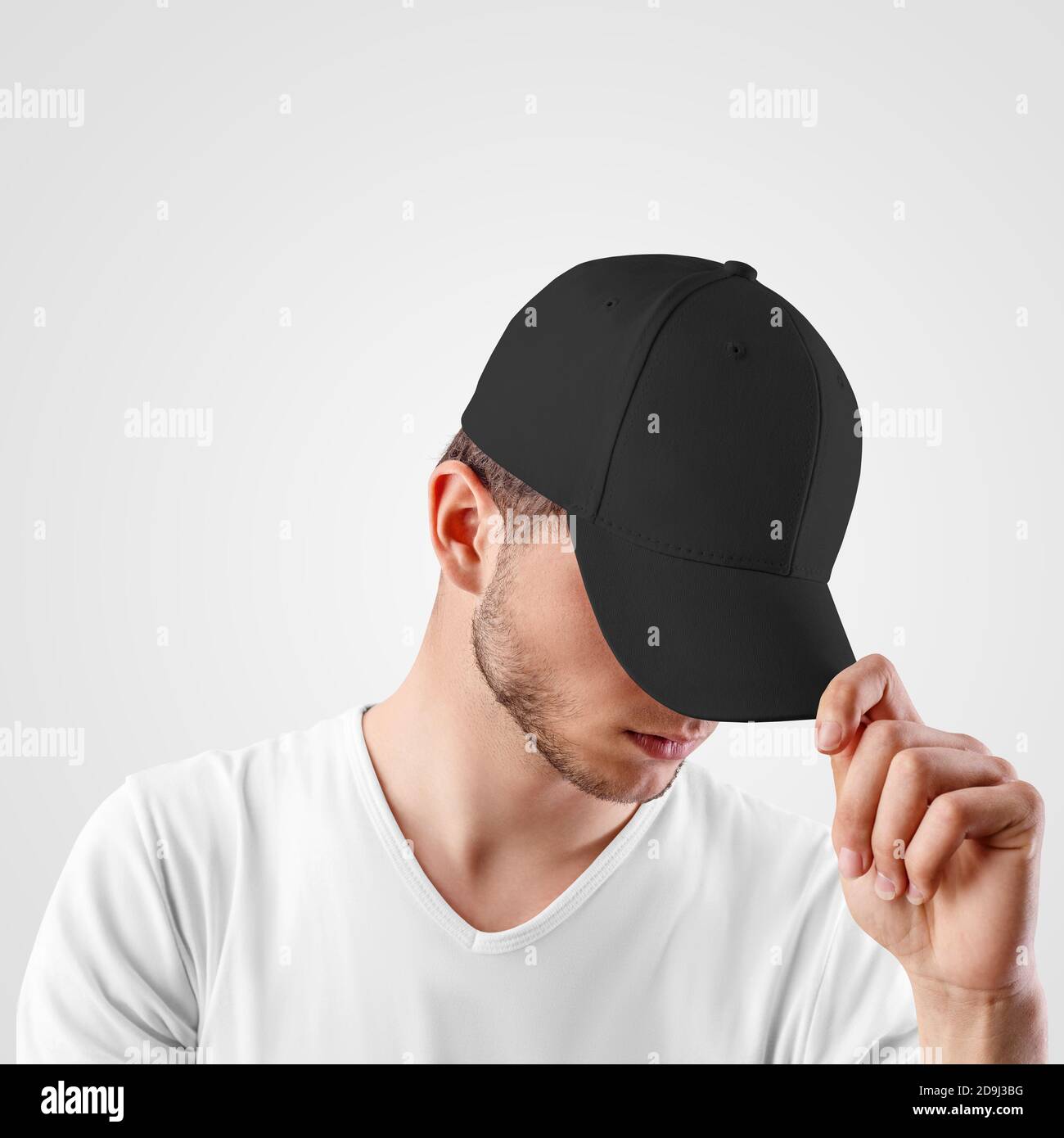 Una gorra negra de béisbol en la cabeza de un chico, mirando desde debajo  de una visera, vista frontal, panamá vacío para la presentación de diseño.  Protección solar Headdress Fotografía de stock -