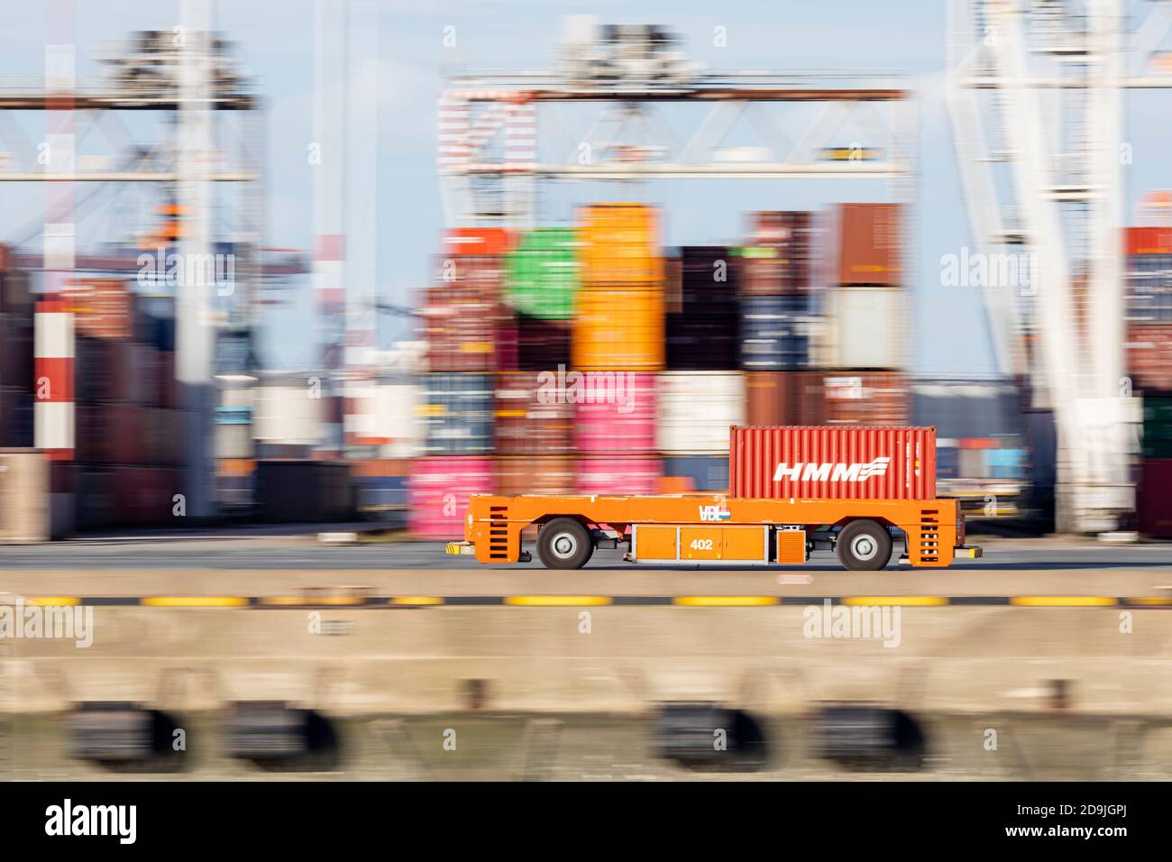 Disparo panorámico del vehículo guiado automático que lleva un contenedor El muelle de una terminal portuaria de Rotterdam Foto de stock