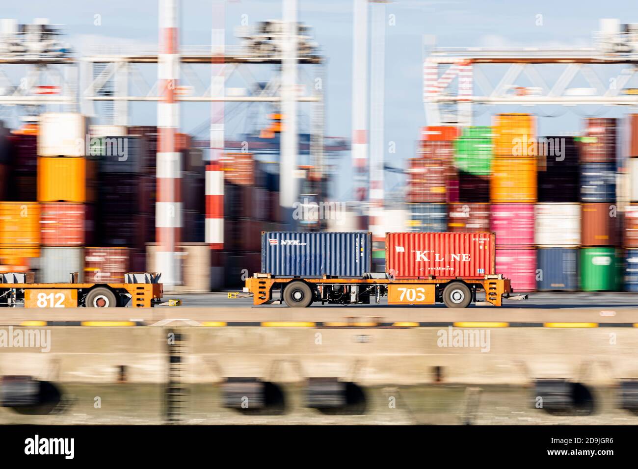 Disparo panorámico del vehículo guiado automático que lleva dos contenedores El muelle de una terminal portuaria de Rotterdam Foto de stock