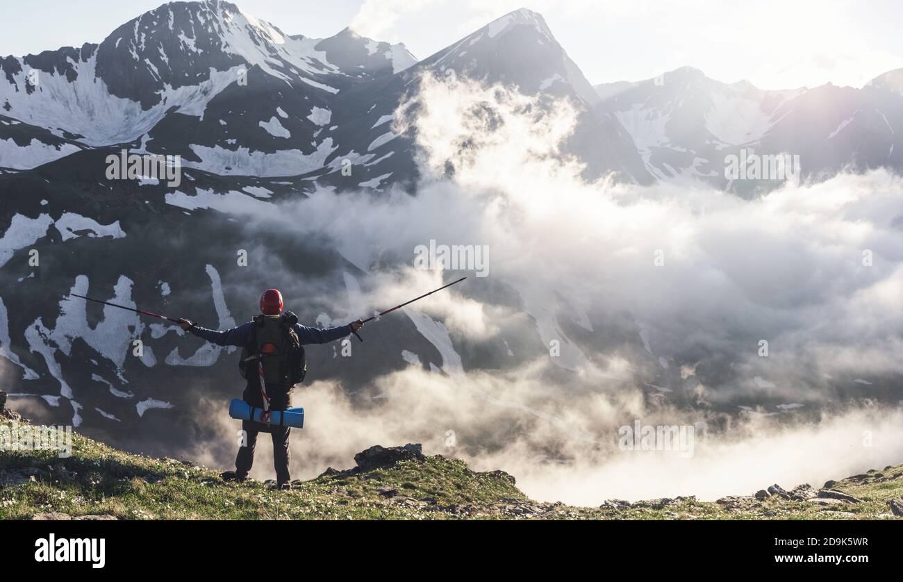 Hombre senderismo en las montañas viajar estilo de vida escalada solo a la cumbre por encima de las nubes vacaciones activas de verano aventura al aire libre Foto de stock