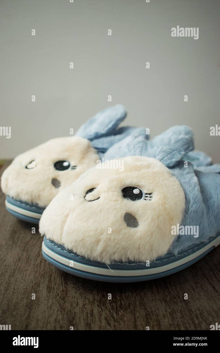 conejito azul zapatillas suaves en una superficie de madera para llevar en casa Foto de stock