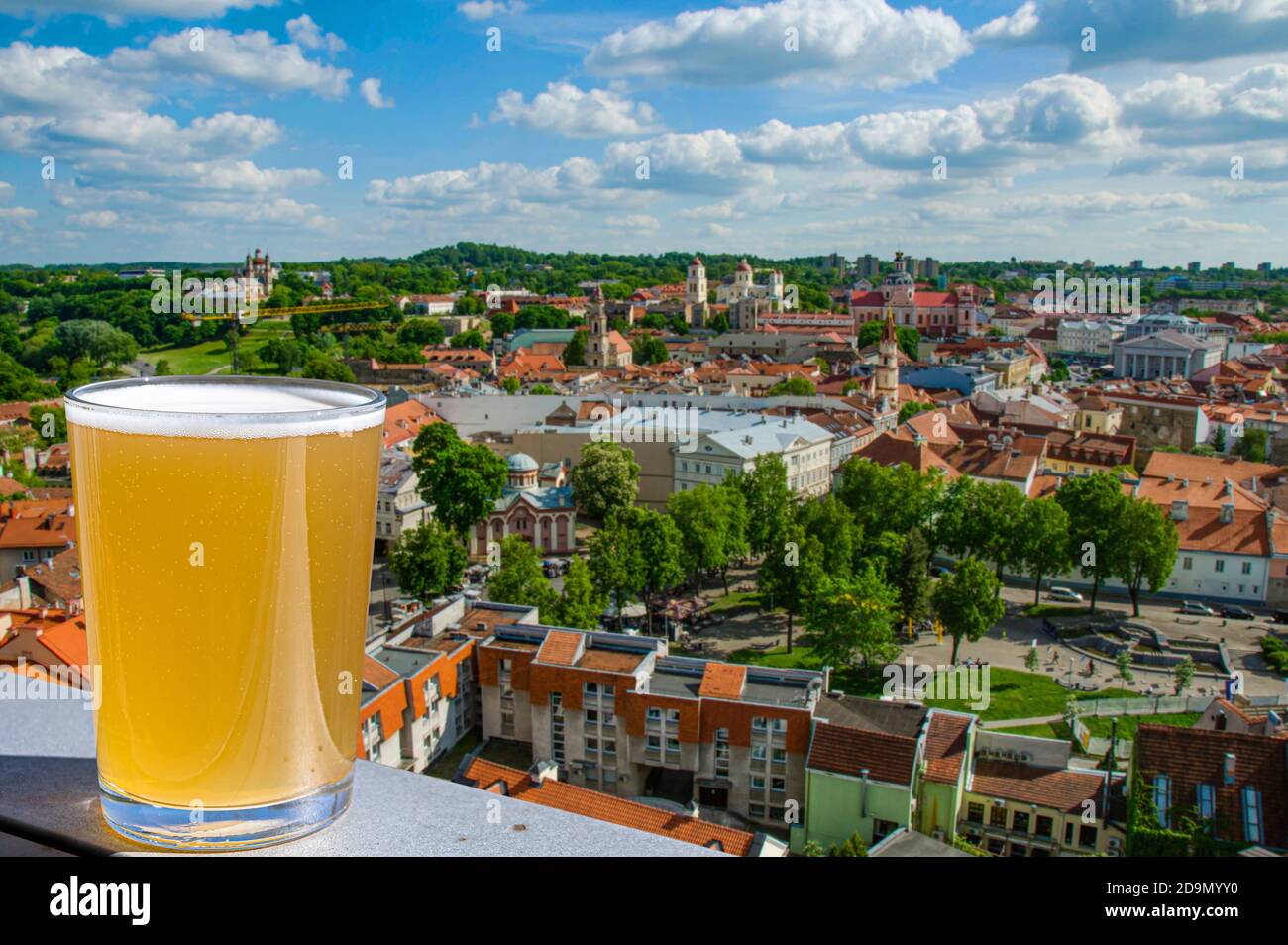 Copa de cerveza ligera contra la vista desde arriba del centro histórico de la ciudad en Vilnius, Lituania Foto de stock