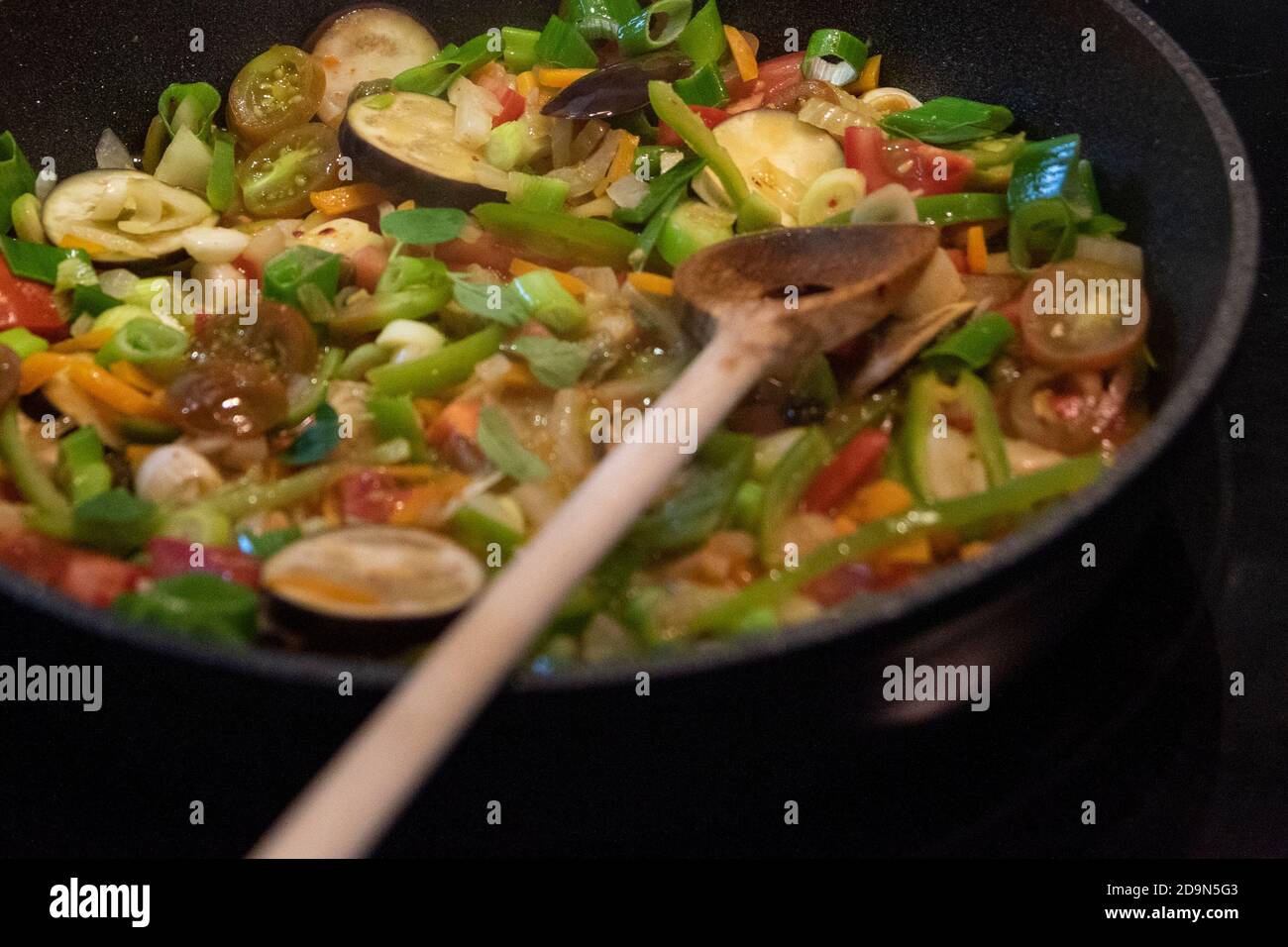Cosechando berenjenas y cocinándolas vegetarianas: Nutrición saludable y sostenible desde tu propio jardín. Preparación de una salsa vegetal con berenjena. Foto de stock