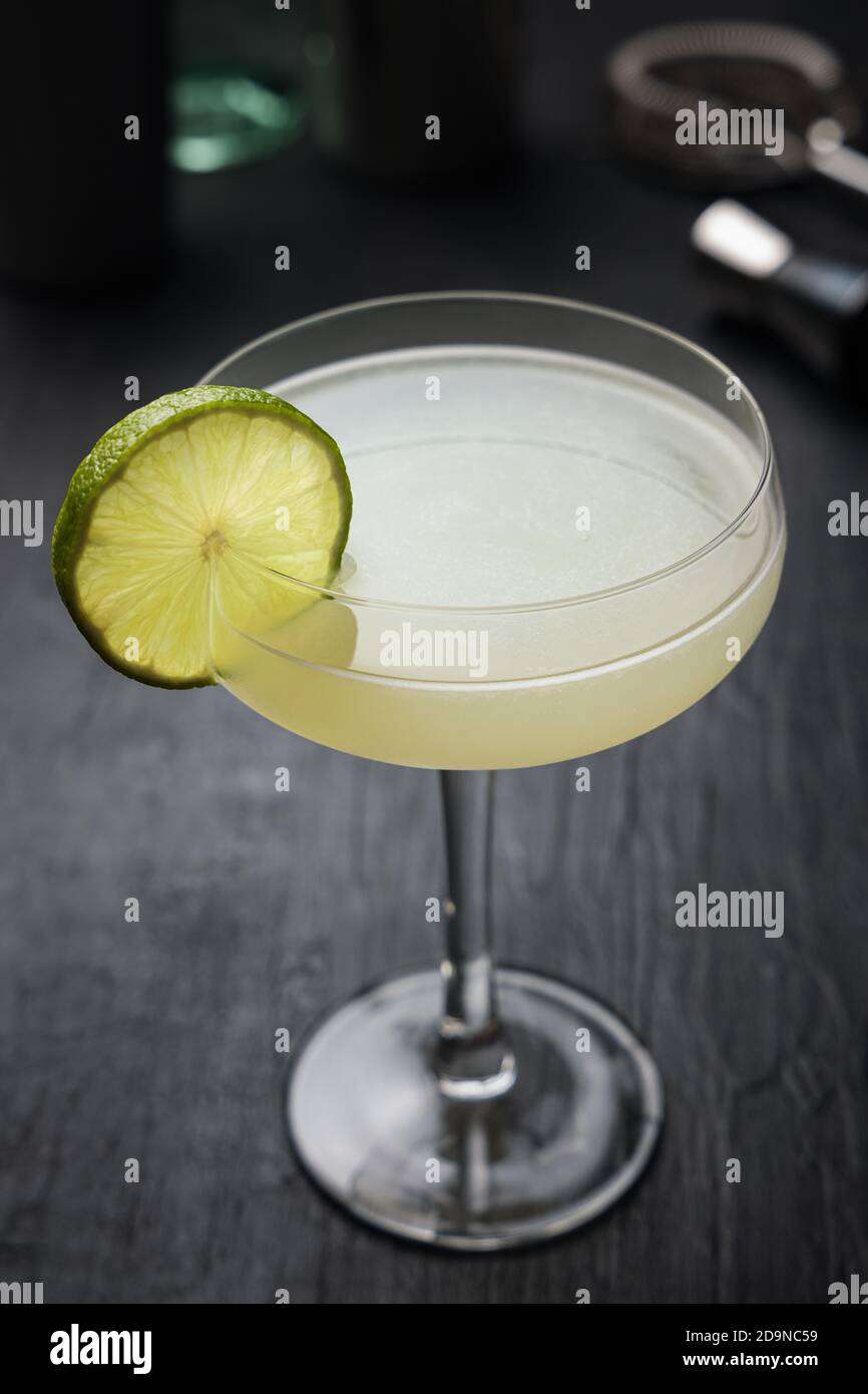 Cóctel Daiquiri clásico con rueda de lima sobre negro tabla Fotografía