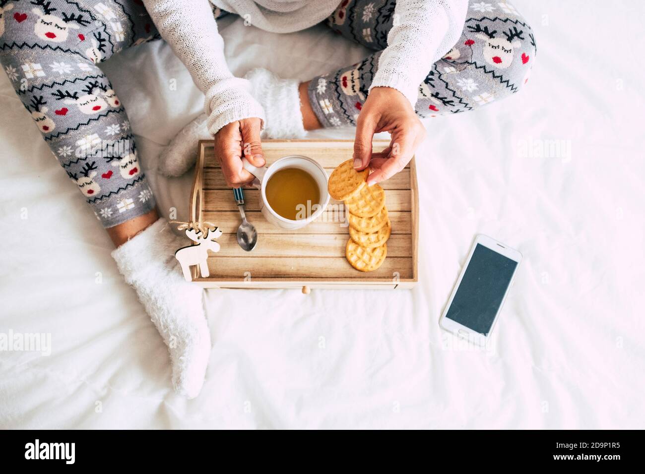 Vista superior de la mujer caucásica hacer el desayuno en la cama una cubierta blanca - decoraciones de ventana y temas - blanco fondo y navidad concepto de estilo de vida para la gente Foto de stock
