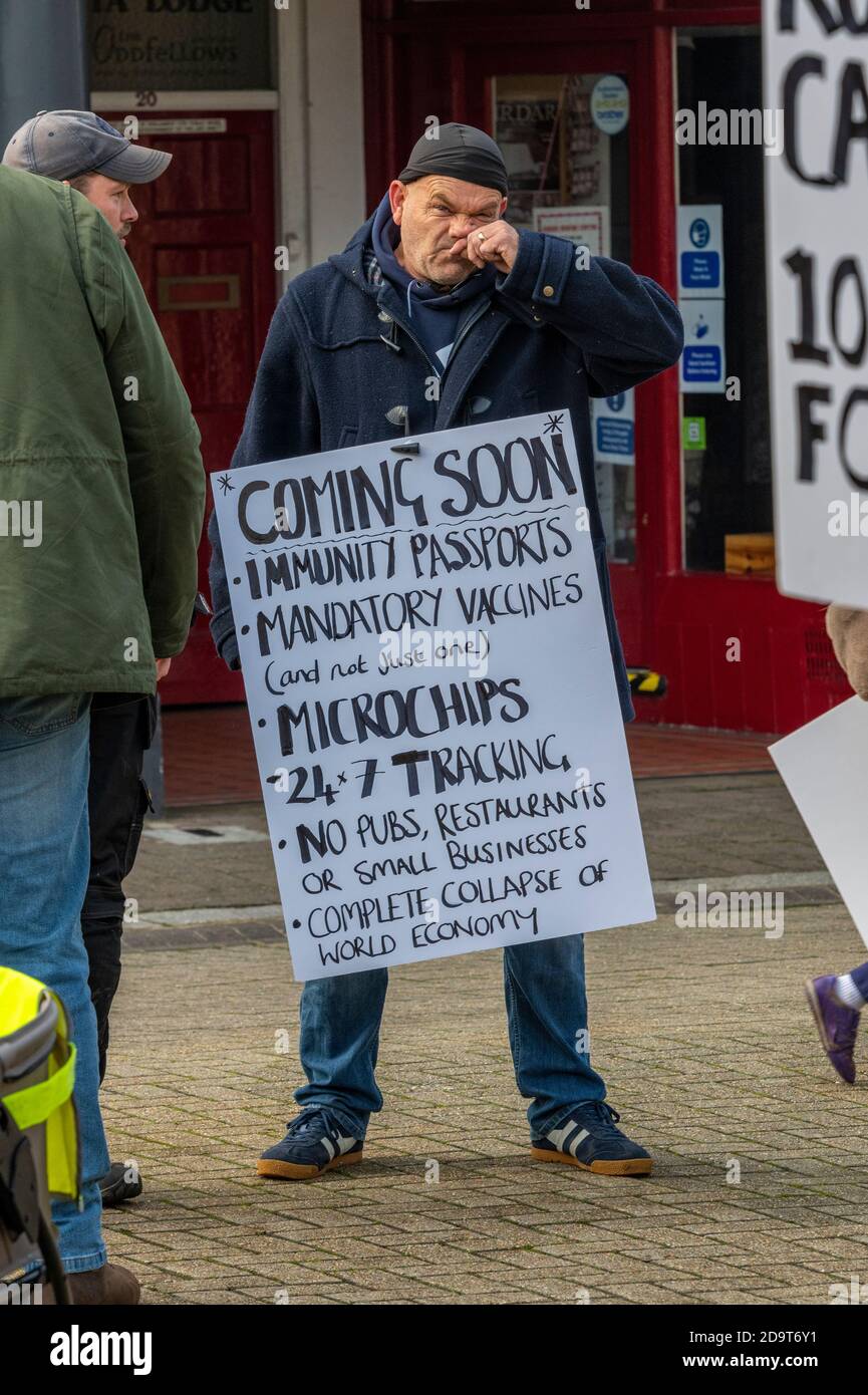 un manifestante o un manifestante que lleva un cartel en una manifestación o manifestación contra el gobierno covid 19 coronavirus polcies y handli. Foto de stock